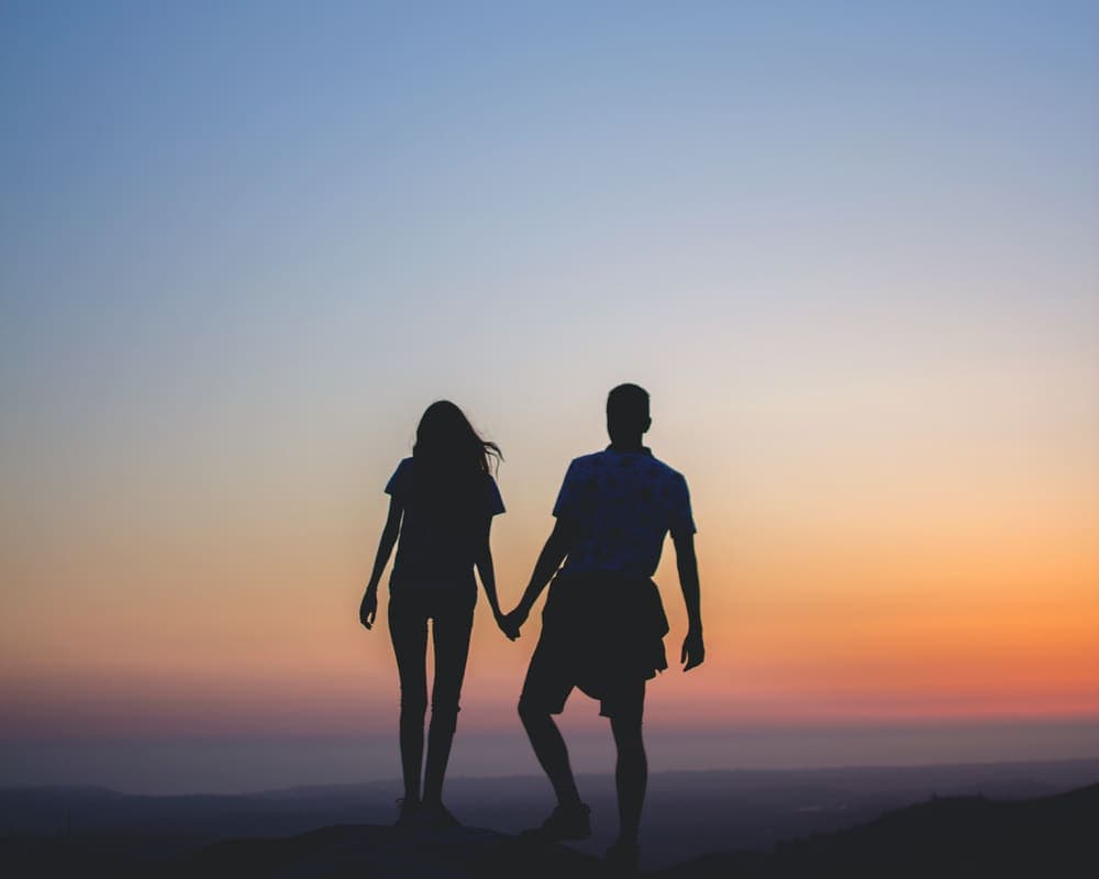 Two travellers on a beach at sunset