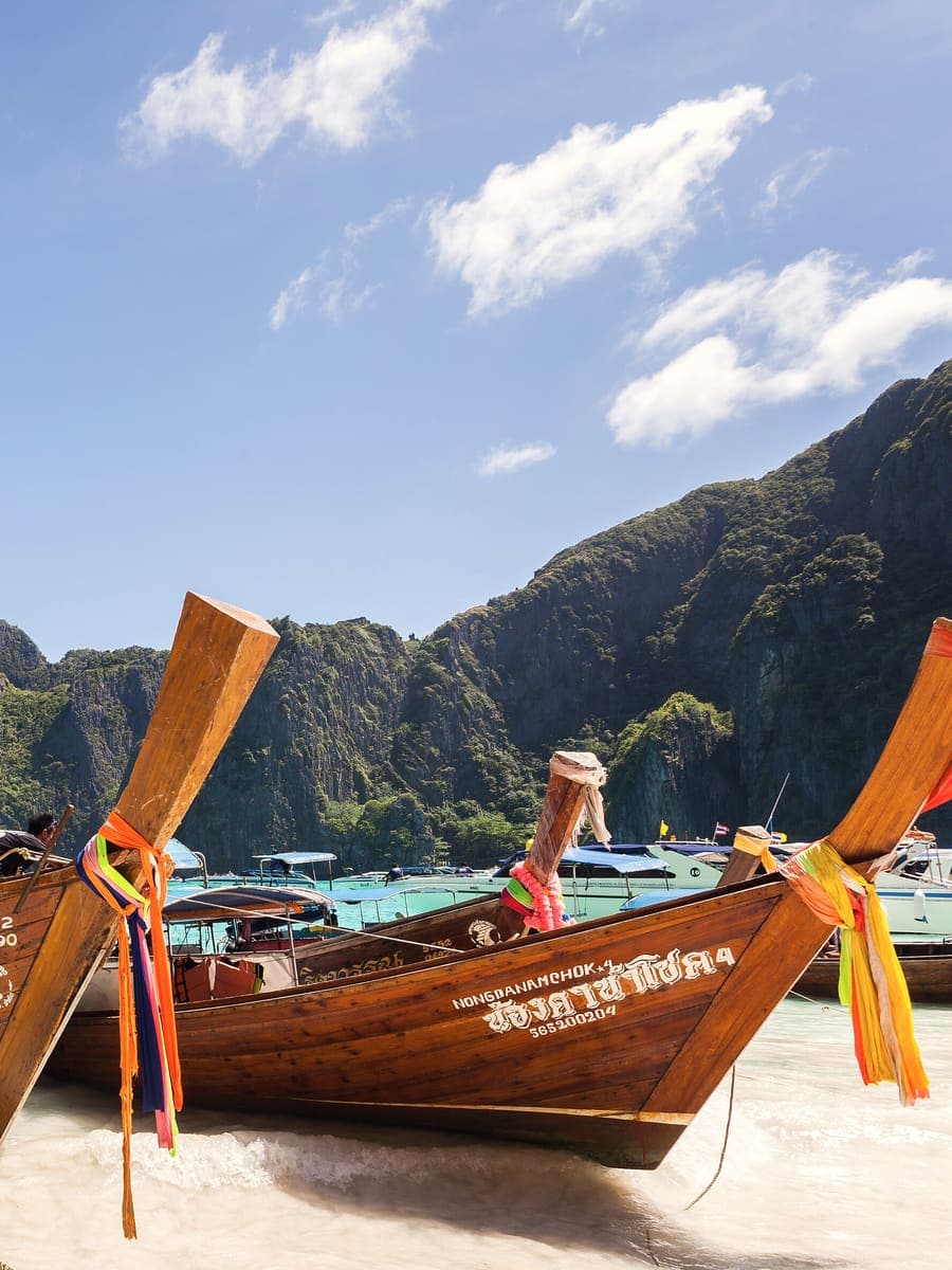 Longtail boats moored below the limestone cliffs of Phi Phi