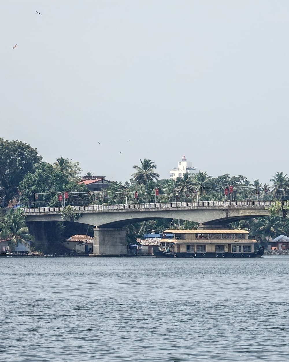 A houseboat passing under a bridge on the Kerala backwaters