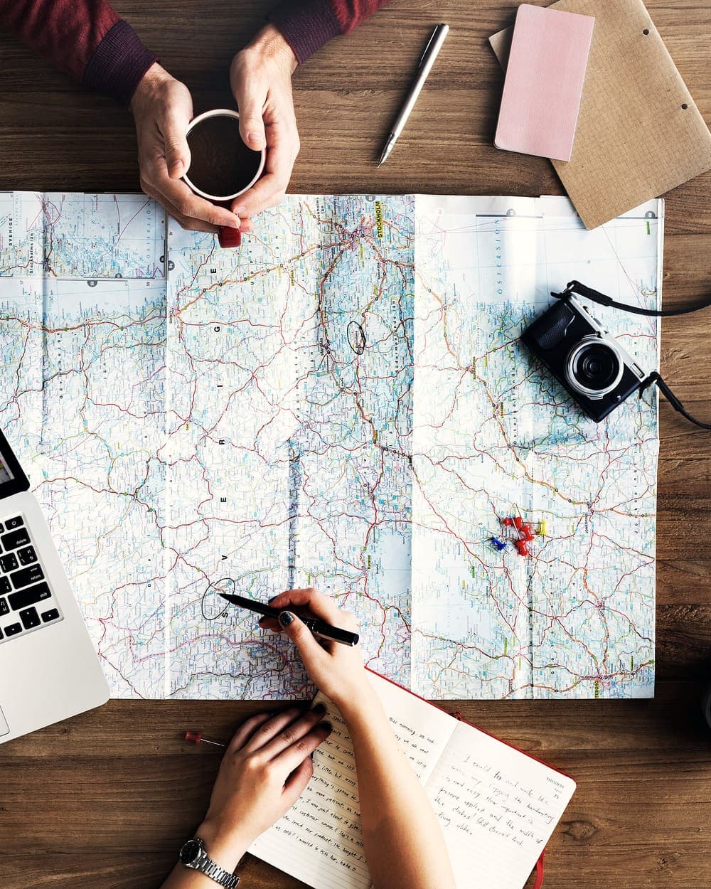 A road map, camera and laptop laid out while planning a trip